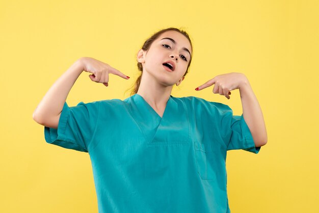 Front view of female doctor in medical suit on yellow wall