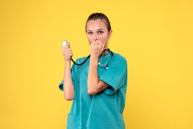 Front view of female doctor in medical suit on yellow wall