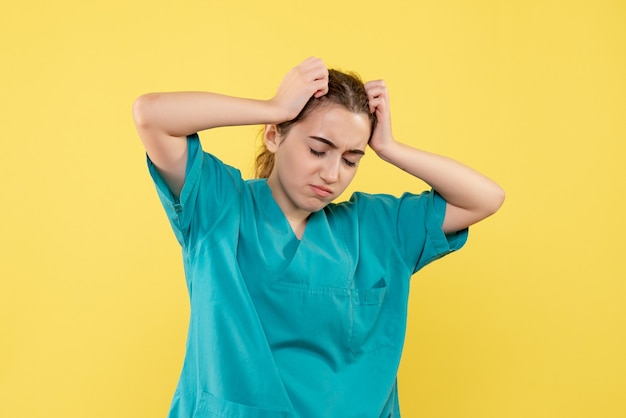 Vista frontale della dottoressa in tuta medica sulla parete gialla