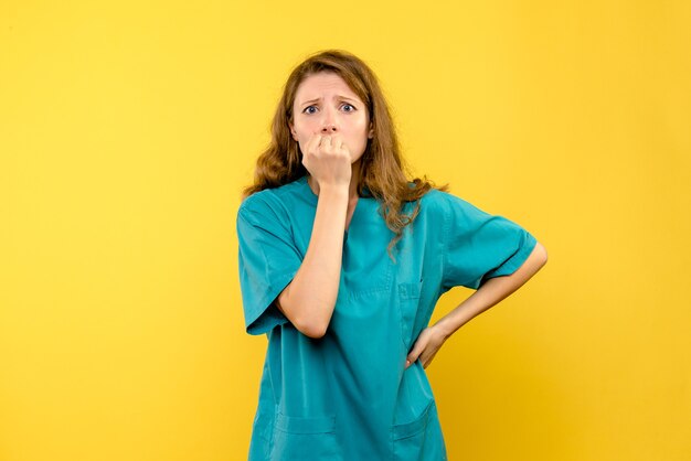 Front view of female doctor nervous on yellow wall