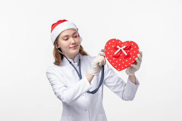 Front view of female doctor observing holiday present on white wall