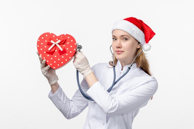 Front view of female doctor observing holiday present on white wall