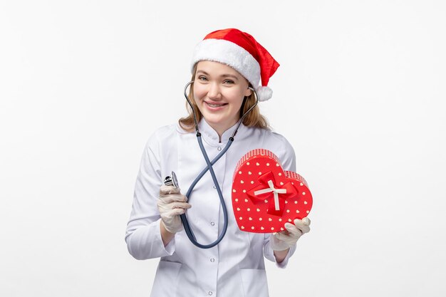 Front view of female doctor observing holiday present on white wall