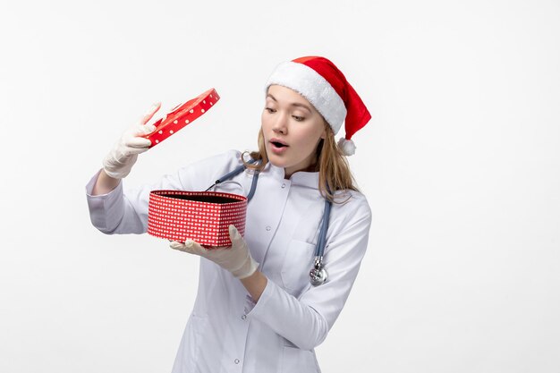 Front view of female doctor opening holiday present on white wall