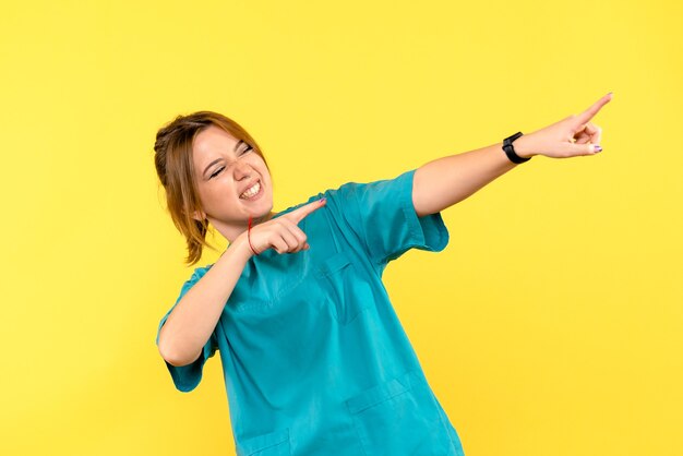 Front view female doctor pointing at distance on yellow space