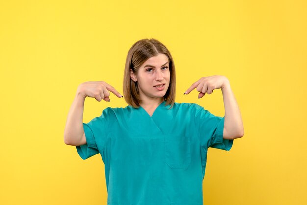 Front view female doctor pointing out on yellow space