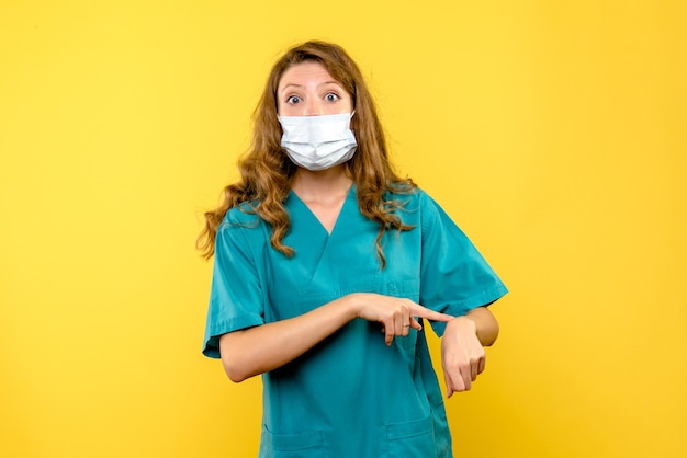 Front view female doctor pointing at wrist on yellow space