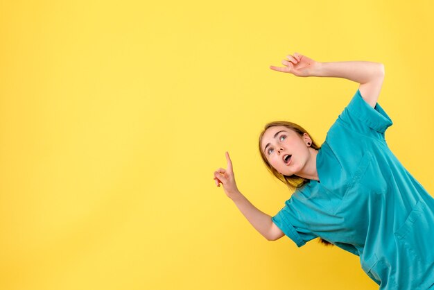 Front view female doctor pointing on yellow background medic emotion virus hospital health