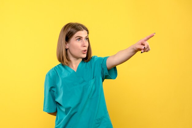 Front view female doctor pointing on a yellow space