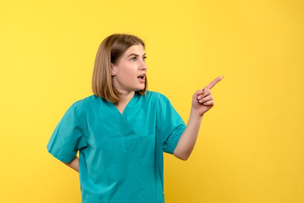 Front view female doctor pointing on yellow space