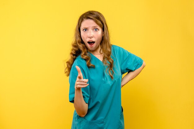 Front view of female doctor pointing on yellow wall