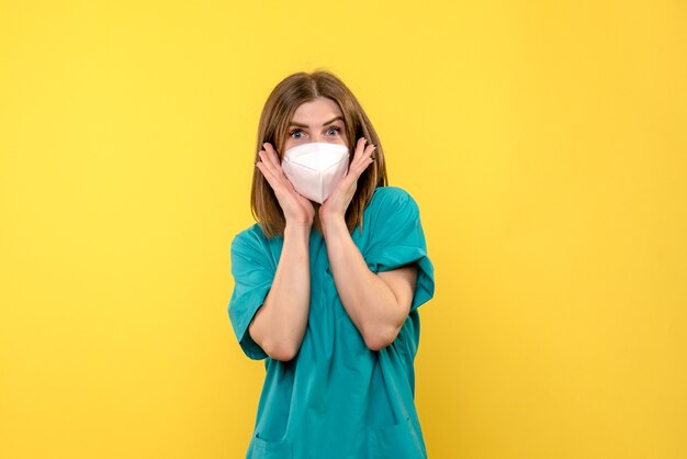 Front view female doctor posing with mask on yellow space