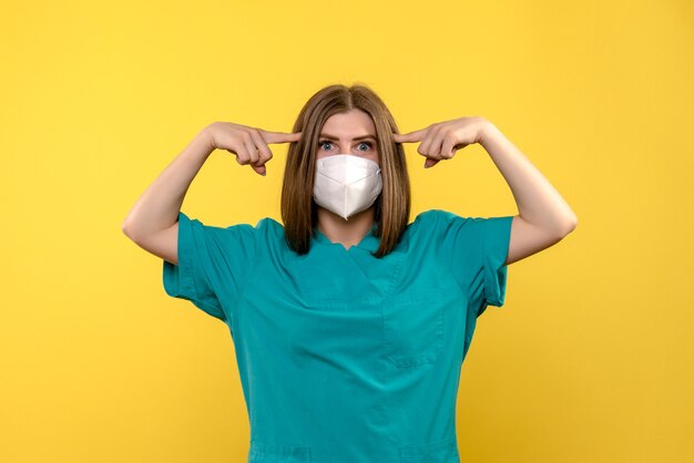 Front view female doctor posing on yellow floor hospital virus pandemic