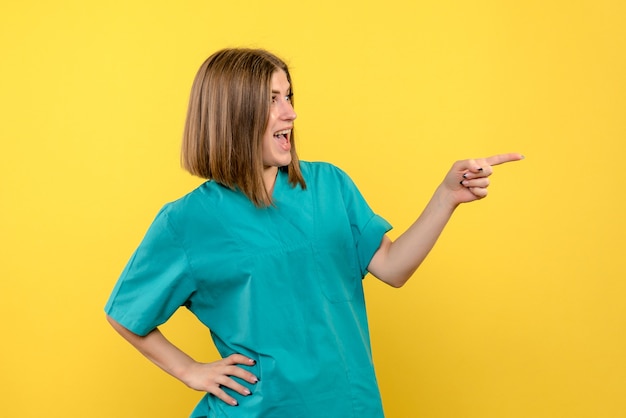 Free photo front view female doctor posing on a yellow space