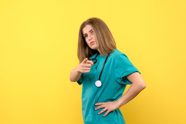 Front view female doctor posing on a yellow space