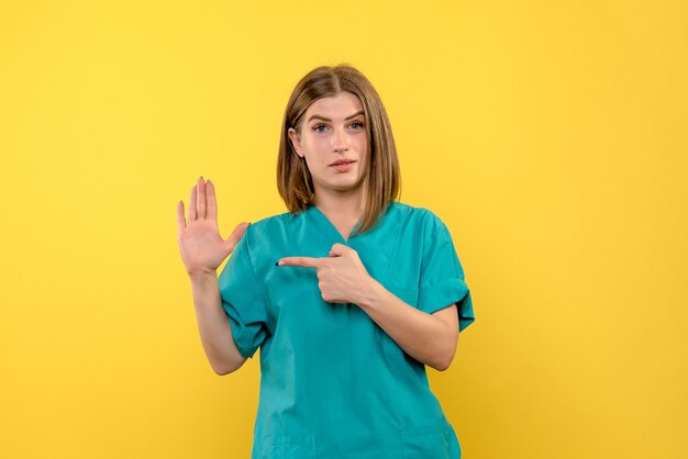 Front view female doctor posing on yellow space