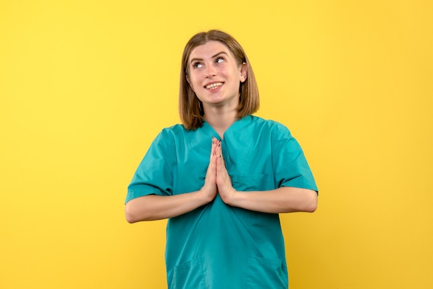 Foto gratuita medico femminile di vista frontale che prega sullo spazio giallo