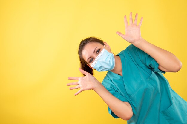 Front view female doctor in protective mask on yellow background