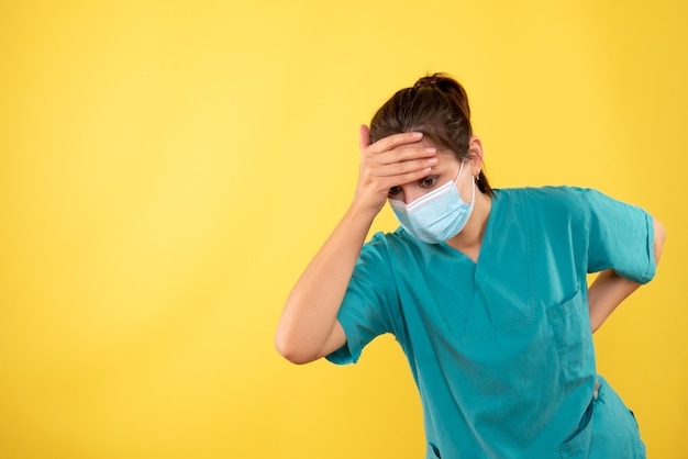 Front view female doctor in protective mask on yellow background