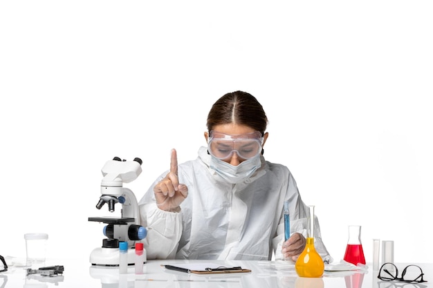 Front view female doctor in protective suit and with mask holding blue solution on white background covid pandemic virus coronavirus