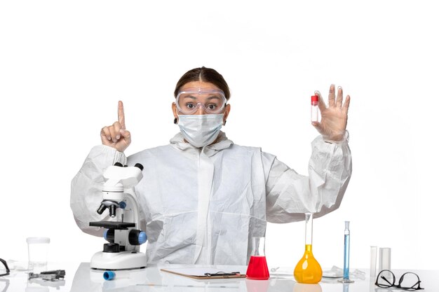 보호 복과 밝은 흰색 배경에 빈 플라스크를 들고 마스크가있는 전면보기 여성 의사 대유행 바이러스 코로나 바이러스 covid 건강