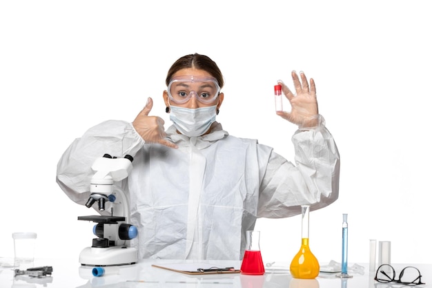 Front view female doctor in protective suit and with mask holding empty flask on light white background pandemic virus coronavirus covid health