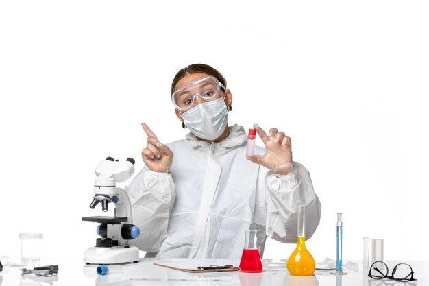 Front view female doctor in protective suit and with mask holding empty flask on a white background covid pandemic virus coronavirus health