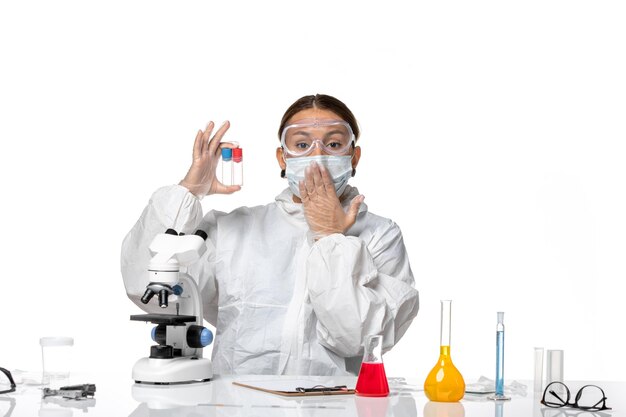 보호 복과 밝은 흰색 배경에 빈 플라스크를 들고 마스크가있는 전면보기 여성 의사 covid pandemic virus coronavirus