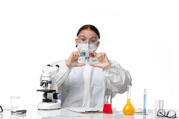 Front view female doctor in protective suit and with mask holding empty flasks on white background covid health pandemic virus coronavirus