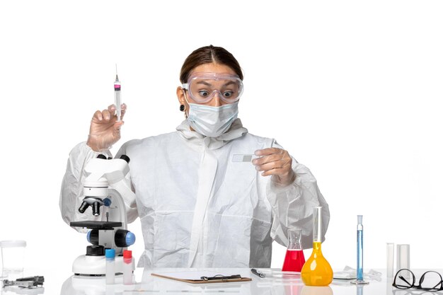 Вид спереди женщина-врач в защитном костюме и с маской, держащей инъекцию на белом фоне, пандемическое здоровье коронавируса вируса covid