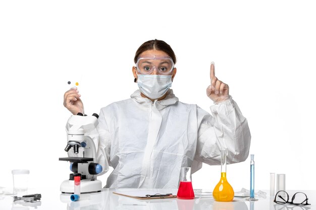 Front view female doctor in protective suit and with mask holding little samples on white background medicine health pandemic virus coronavirus