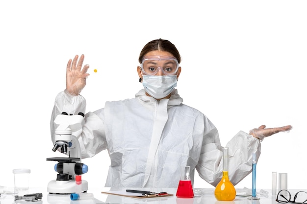 Free photo front view female doctor in protective suit and with mask holding sample on light-white background medicine covid- pandemic virus