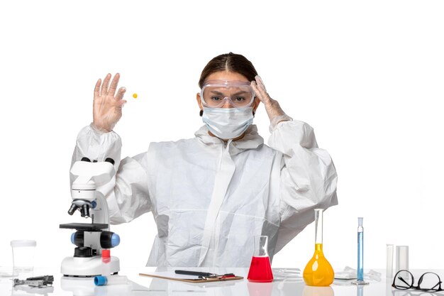 Front view female doctor in protective suit and with mask holding sample on a white background medicine covid- health pandemic virus