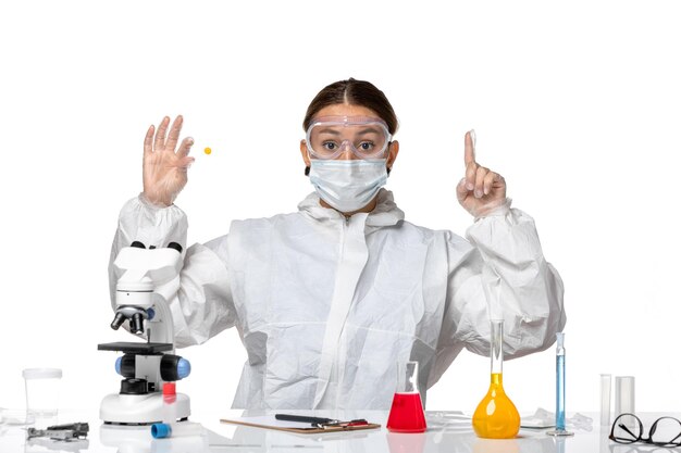 Front view female doctor in protective suit and with mask holding sample on white background medicine covid- health pandemic virus