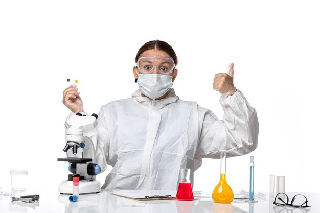 Front view female doctor in protective suit and with mask holding samples on light-white background medicine health pandemic virus coronavirus