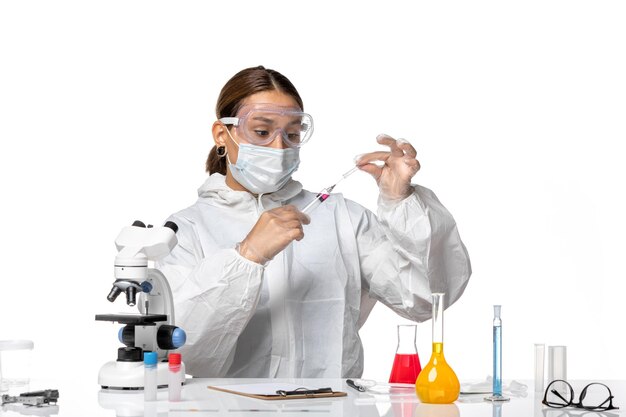 Вид спереди женщина-врач в защитном костюме и с маской, использующая инъекцию на белом фоне, пандемический коронавирус, вирус коронавируса здоровья