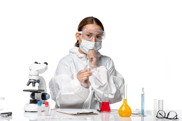 Front view female doctor in protective suit and with mask working with solutions thinking on white background covid pandemic virus coronavirus