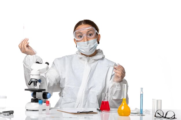防護服を着た正面図の女性医師と白い背景のソリューションで作業するマスクcovidウイルスパンデミックコロナウイルス