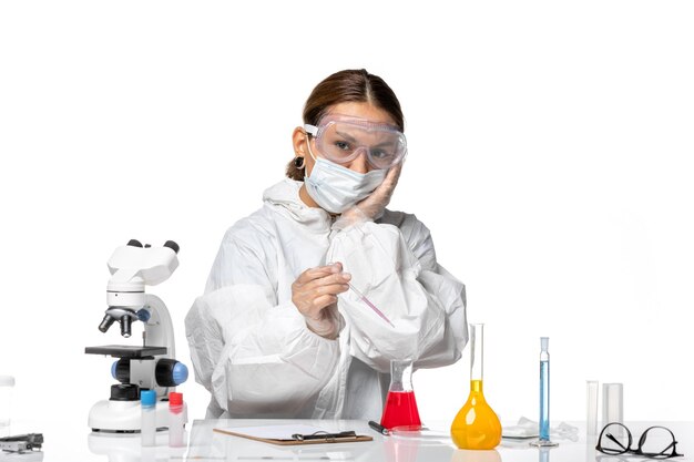 보호 복과 마스크가있는 전면보기 여성 의사가 흰색 책상 covid 유행성 바이러스 코로나 바이러스에 대한 솔루션 작업