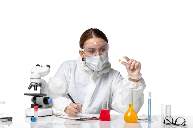 Front view female doctor in protective suit and with mask writing notes on white background medicine covid- health pandemic virus