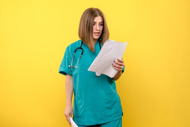 노란색 공간에 파일을 읽는 전면보기 여성 의사