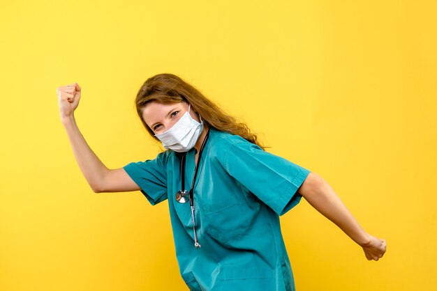 Front view female doctor rejoicing in mask on yellow space