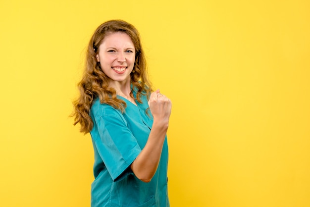 Front view of female doctor rejoicing on yellow wall