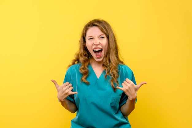 Front view of female doctor rejoicing on yellow wall