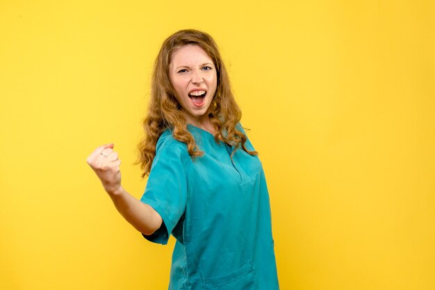 Front view of female doctor rejoicing on yellow wall