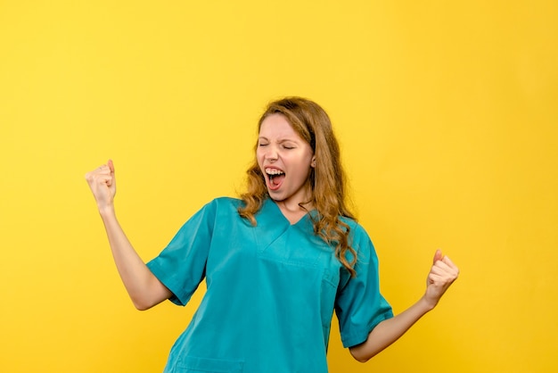 Front view of female doctor rejoicing on yellow wall