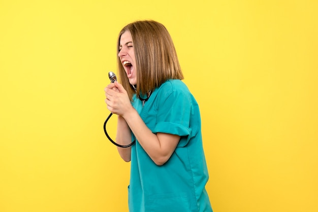 Front view female doctor screaming at tonometer on yellow space