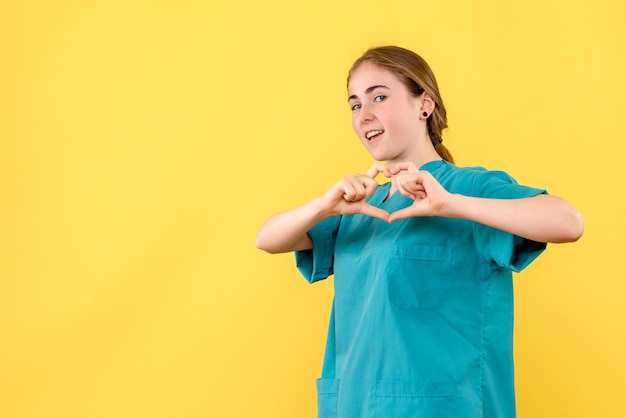 Foto gratuita medico femminile di vista frontale che trasmette amore sull'emozione del virus dell'ospedale di salute del medico del fondo giallo