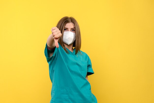 Front view female doctor showing unlike sign on a yellow space