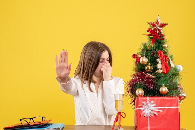 Front view female doctor sitting in front of her table on yellow background